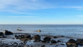 Coastal rocks covered with green algae and soft waves under a bright sky. Natural shoreline texture suitable for documentaries, backgrounds, wellness content and marine visuals. - Powered by Shutterstock - Get 15% off with code: PIKWIZARD15