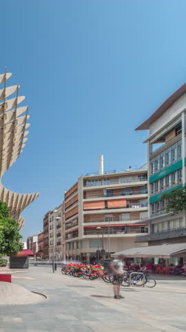 Metropol Parasol in Encarnacion Square timelapse hyperlapse, a futuristic wooden structure with a panoramic walkway and an archaeological museum. Blue sky, trees and cityscape in Seville, Spain.