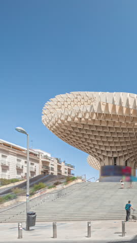 Metropol Parasol in Encarnacion Square timelapse hyperlapse, futuristic wooden structure with panoramic walkway and an archaeological museum. Blue sky, stairs, traffic and cityscape in Seville, Spain