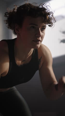 Determined Caucasian muscular build woman athlete in sportswear, doing cardio exercises during cross bodyweight workout, battling ropes in smokey gym interior. People. Bodybuilding. Sport. Endurance