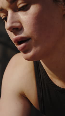 Headshot confident female athlete weightlifte engaged in sports routine, wiping off sweat, breathing deeply, relaxing after heavy training in dark smokey gym interior