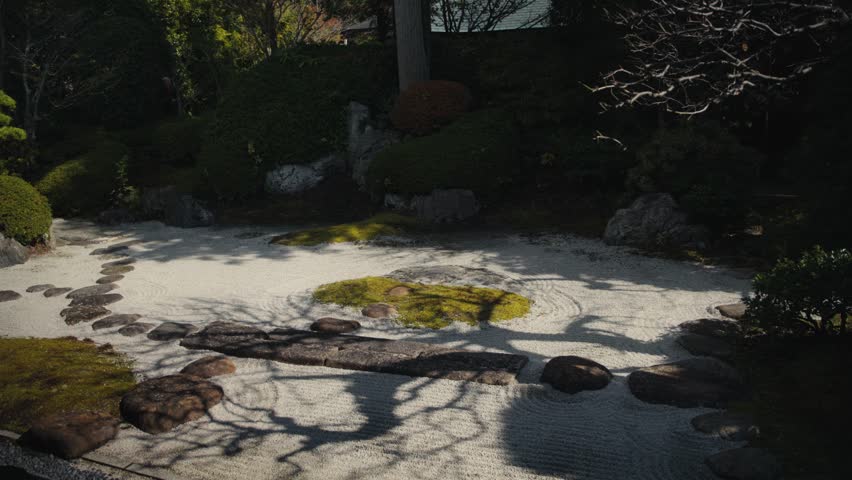 Tree shadows moving on raked sand in a japanese zen garden