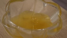 Golden honey drips into a clear glass bowl, forming a smooth, thick pool with a glossy texture and rich amber tone on a wooden surface, emphasizing natural sweetness and viscous movement in close up - Powered by Shutterstock - Get 15% off with code: PIKWIZARD15