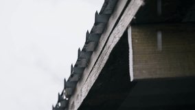 Rainwater pours continuously from the jagged edge of a corrugated metal roof overhang. The gray overcast sky provides a bleak backdrop to the rhythmic falling of water drops from the structure. - Powered by Shutterstock - Get 15% off with code: PIKWIZARD15
