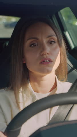 Bad-tempered young lady driving automobile with safety bell and feeling irritated when being cut off on highway. Angry female person yelling, gesturing hands and beeping horn.