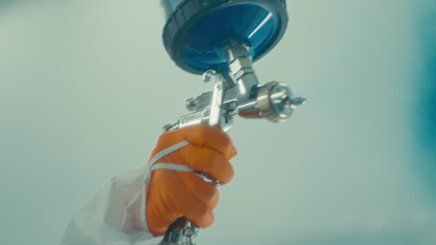 Worker Spraying Glass Panel with Blue Paint