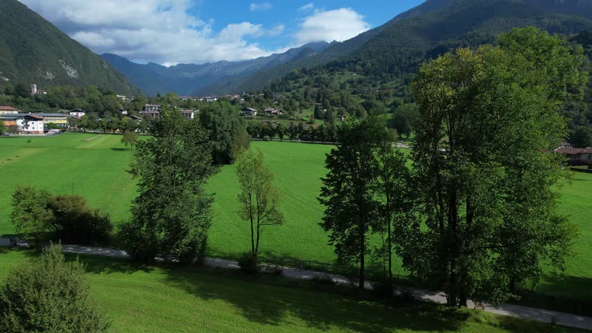 Aerial shot of Valle di Ledro showing green meadows trees and mountain landscape on a clear day