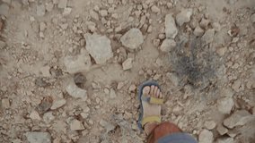 POV of person walking with sandals on rocks and dry ground in desert terrain. Top down shot personal perspective point of view of hiker or traveler in natural park or in wilderness climbing hill - Powered by Shutterstock - Get 15% off with code: PIKWIZARD15