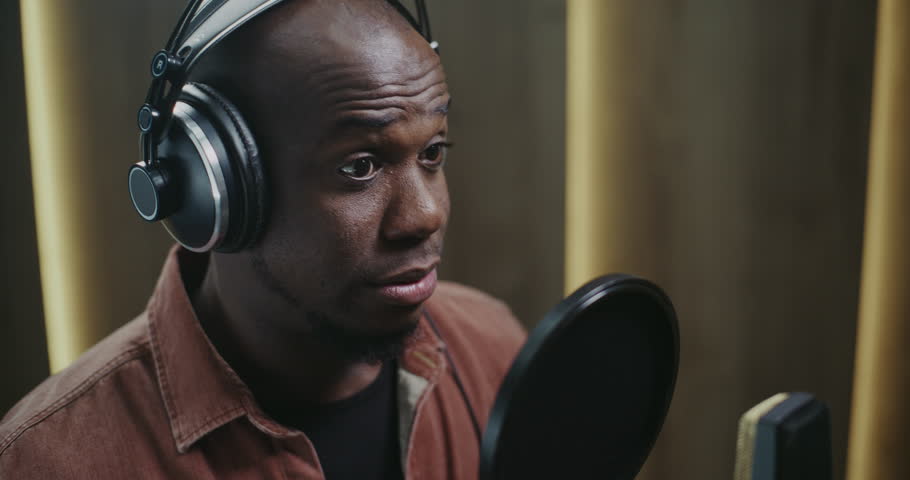 Male Voice Actor Delivering Dynamic Film Dubbing. Wearing Headphones and Facing Studio Microphone With Pop Filter, Man Records Expressive Lines With Strong Character Emotion and Vocal Precision.