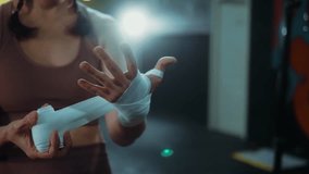 Close-up of a woman wrapping her hand with bandages, focused and precise as she prepares for an intense boxing training session in a gym.	 - Powered by Shutterstock - Get 15% off with code: PIKWIZARD15