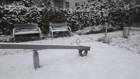 Winter scenery during the first snowfall: a snow-covered bench in a housing estate as snow falls, with frosty and slippery weather in winter or late autumn. - Powered by Shutterstock - Get 15% off with code: PIKWIZARD15