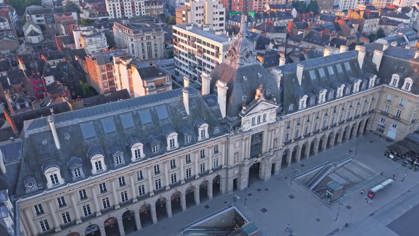 Drone advancing in top-down view over Palais du Commerce in Rennes, France revealing its façade at sunrise.