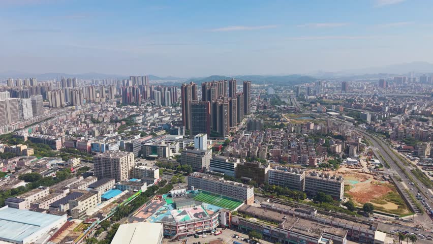 A vast aerial of the Shenzhen outskirts skyline. Captures the intense urban sprawl and development, contrasting the core high-rises with surrounding lower-density areas and open lots. China, UHD.