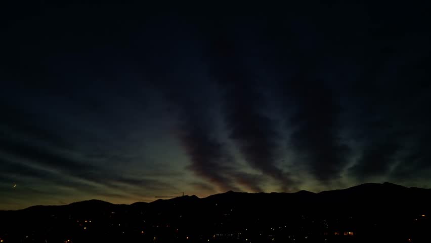Lugano, Switzerland – August 7 2024: Darkening night sky over the Italian-Swiss border mountains toward Monte Limidario and Riserva Naturale Monte Mottac, with crescent moon faintly visible above the 