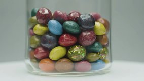 Vibrant, glittery candies in a glass jar, gently rotating to showcase their glossy texture and rich colors. Perfect for sweet treat advertising and joyful content. - Powered by Shutterstock - Get 15% off with code: PIKWIZARD15
