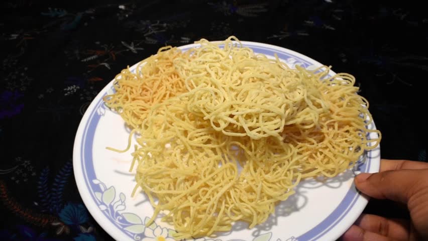 freshly fried noodles served on a plate, placed on a dinner table setting for soup or chopsuey