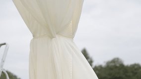 The white fabric of the wedding arch sways in the gusts of wind. - Powered by Shutterstock - Get 15% off with code: PIKWIZARD15