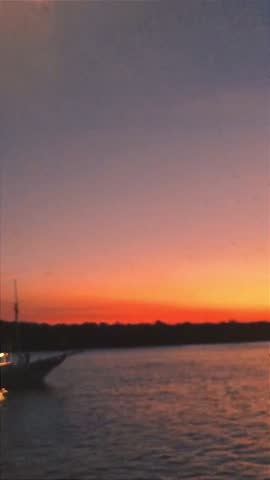 Dramatic Orange Sunset Over River with Fishing Boat