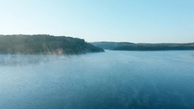 High quality video showing a calm lake at dawn with soft mist drifting across the water and gentle morning light over distant hills. - Powered by Shutterstock - Get 15% off with code: PIKWIZARD15