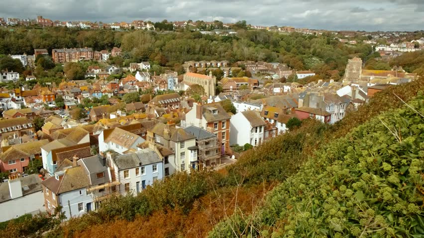 A wide coastal view showcases a historic town with charming buildings along the shoreline, blending scenic seaside landscapes with rich cultural and architectural heritage.