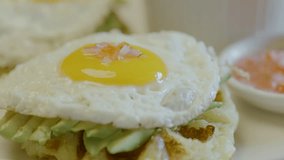 Close-up of a breakfast with a soft-yolk fried egg on avocado and waffle base, while a cutlery cuts the yolk. - Powered by Shutterstock - Get 15% off with code: PIKWIZARD15