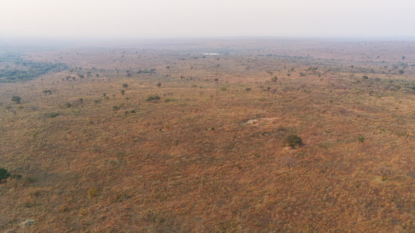 A wide aerial view reveals sparse vegetation and open terrain, highlighting the vastness of Kruger National Park.