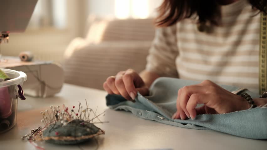 Close-Up Of A Woman Pinning Fabric Before Setting Up A Sewing Machine