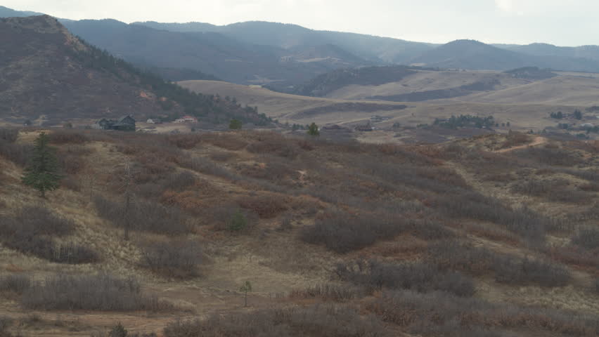 Aerial of dry grassy hillsides in Sedalia Colorado in fall on cloudy day
