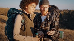 Red bearded man shows map on smartphone to African American girlfriend on hike. Young diverse couple chooses route with mobile phone on autumn valley hill - Powered by Shutterstock - Get 15% off with code: PIKWIZARD15