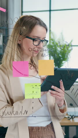 Business concept where adorable confident woman working on glass board with datas and charts and calculating possible options to get best results in start up project