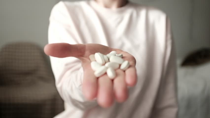 Woman holds medical pills on palm. Woman opens hand full of medical supplements. Soft focus and natural light tablets, cinematic slow motion video of various medicine supplements. Healthcare product.