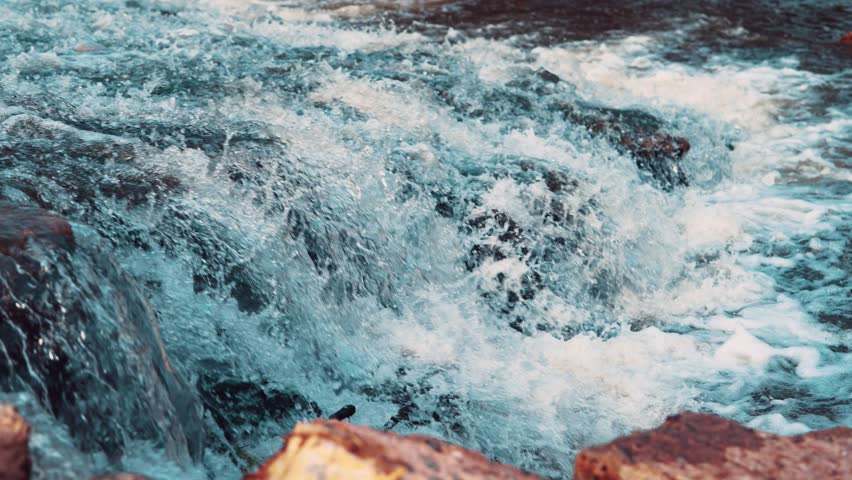 White foam and splashing water flowing over dark submerged rocks