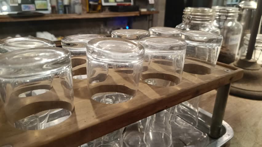A clean arrangement of clear glasses displayed on a wooden rack in a rustic setting, perfect for beverage service or minimalist presentations,