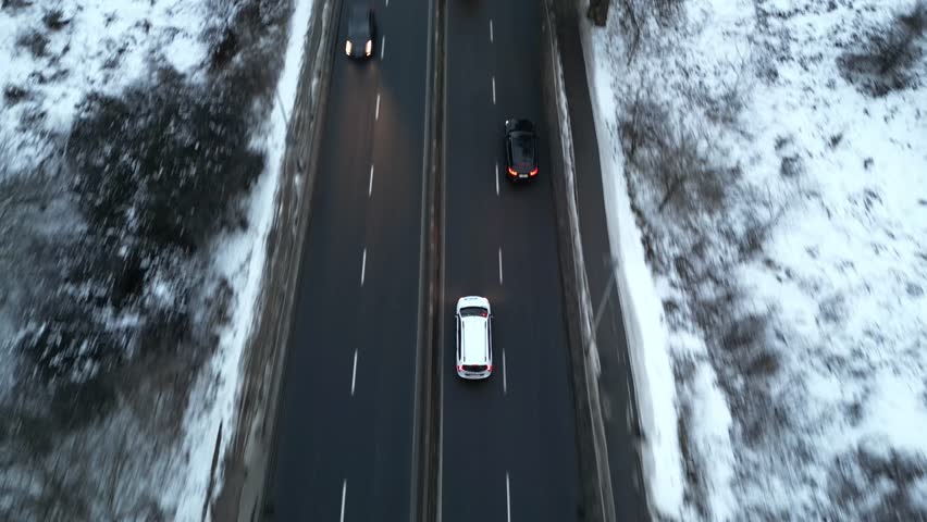 Aerial view of a cars driving along a snow-covered road, showcasing the vehicle