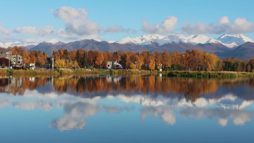 Modern Anchorage Neighborhood by Lake with Autumn Colors and Mountains. People enjoy cycling and walking in a quiet modern district. 