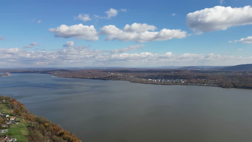 Wide aerial glide across Newburgh with mixed forest, riverscape, and bright daylight.
