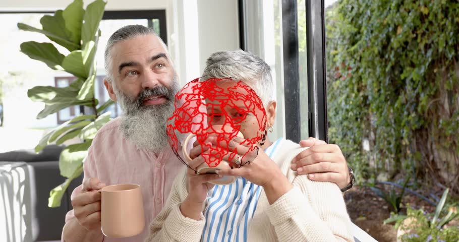 Pair sitting porch holding mugs while AR globe appearing she pointing he following reacting to hack. Couple, mature, sunroom, veranda, garden, cup, ceramic
