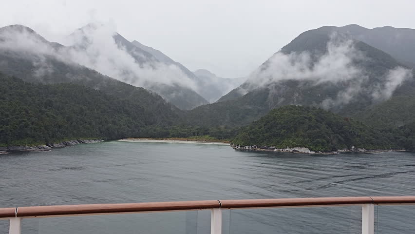 Milford Sound New Zealand fiord landscape on moody foggy day, experiencing travel and tourism in the South Island, with dense forest covering mountains and clouds hanging low