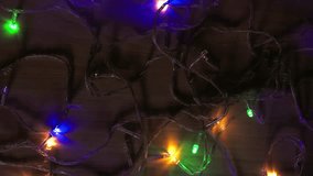 Multicolored LED fairy lights spread randomly on a dim wooden surface, glowing with soft illumination. Warm yellow, green, blue, and purple hues create a cozy and atmospheric loopable background. - Powered by Shutterstock - Get 15% off with code: PIKWIZARD15