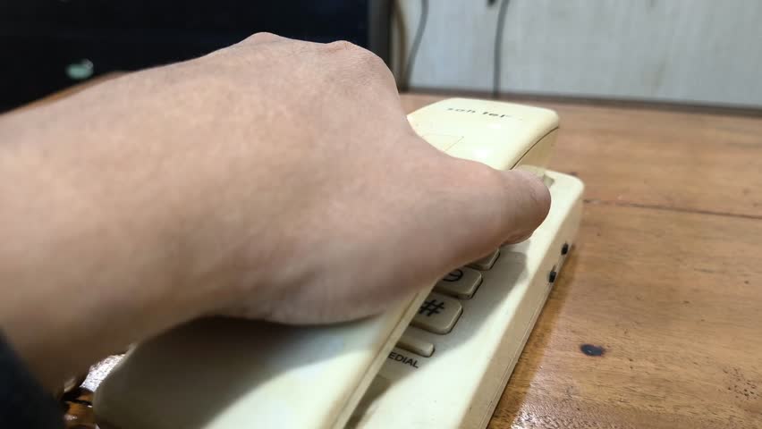 Vintage landline awaits a crucial call. Finger poised to dial on the aged keypad. Hearkening back to simpler times of direct connection, promising urgent communication.