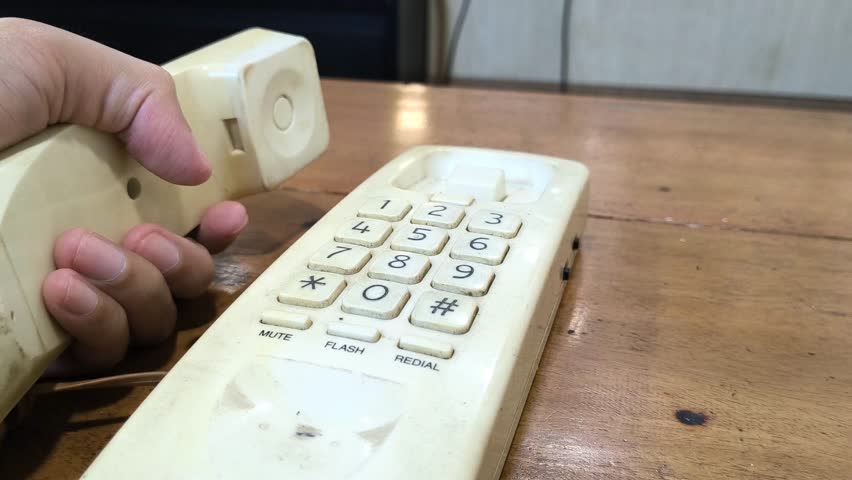 Vintage landline awaits a crucial call. Finger poised to dial on the aged keypad. Hearkening back to simpler times of direct connection, promising urgent communication.