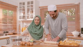 Happy Muslim couple baking bakery together in kitchen at cozy home. Attractive man and woman wearing hijab feel relax and enjoy spending time cooking food and preparing dough on wooden table and love. - Powered by Shutterstock - Get 15% off with code: PIKWIZARD15
