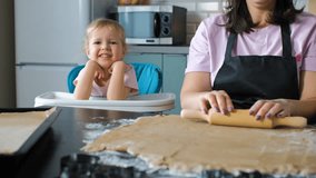 Cute child girl rests her chin on her hands while watching ginger cookie dough being rolled, capturing a gentle family baking moment filled with warmth, slow motion - Powered by Shutterstock - Get 15% off with code: PIKWIZARD15