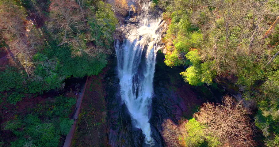 Dry Falls in western North Carolina with clear water cascading through colorful autumn forest. Scenic view along the Mountain Waters Scenic Byway