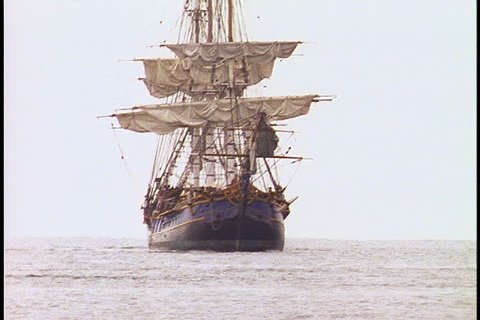 Historical reenactment of HMS Bounty ship on Rhode Island. MS Bounty with furled sails heads directly towards camera on gray choppy water under overcast sky.