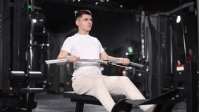 In gym, guy uses cable row machine to strengthen arm muscles. Series of repetitions to consolidate result. Perseverance and persistence in achieving fitness goal. - Powered by Shutterstock - Get 15% off with code: PIKWIZARD15