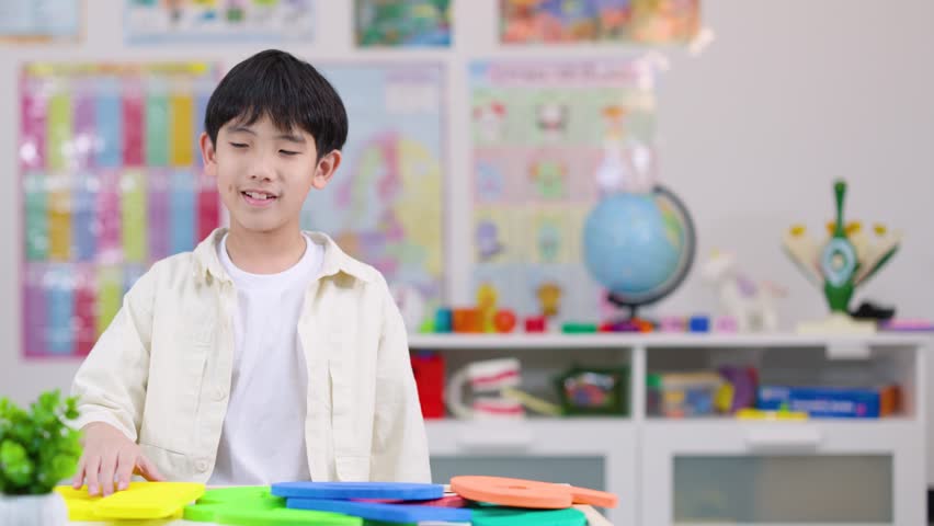 Young boy holds yellow foam number one, smiling in brightly lit educational classroom setting