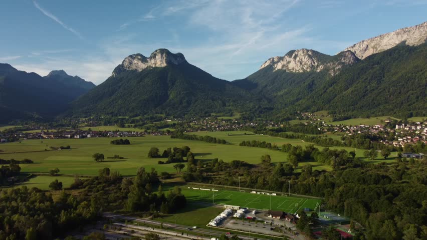 Mountain View over a small town south of Lake Annecy. Drone footages moves slowly to the right showing this impressive view on a bright, summers day.