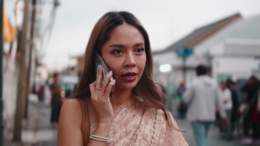 Young thai woman in traditional dress talking on the phone