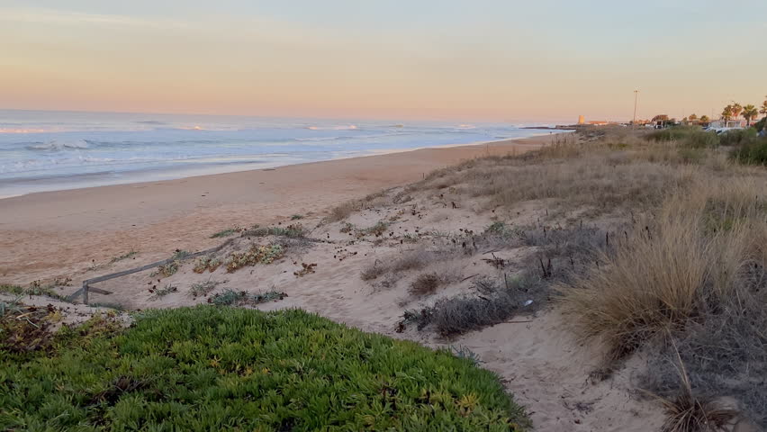 sunrise soft light paints the dunes of El Palmar while Atlantic waves roll in, capturing the calm before another surf session